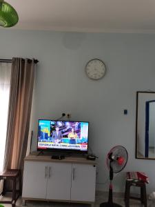 Un televisor en un mueble en una sala de estar con un reloj. en ZG Villa Batu, en Tlekung