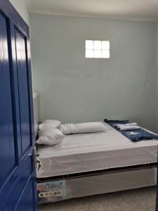 Cama en habitación blanca con puerta azul en ZG Villa Batu, en Tlekung