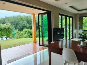 a dining room with a table and a large window at Hana Villa Hatyai in Suen Phra