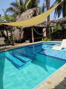 una piscina con una hamaca frente a una casa en Eco Cabañas Keiki Kai, en Sipacate