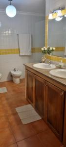 a bathroom with two sinks and a toilet and a mirror at Charmoso Apartamento T2 em Foros de Salvaterra in Monte de Lucas