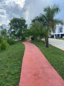 a red path in a park with a palm tree at Casa Brigitte in Cancún