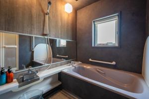 un bagno con ampia vasca e finestra di The Kokage a Nakafurano