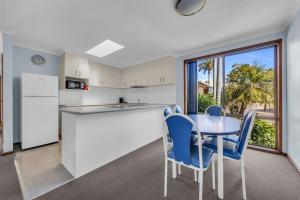 a kitchen with a table and chairs and a window at Anchorbell Apartments Merimbula in Merimbula