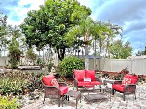 a patio with chairs and a table with red pillows at Beautiful 3 Bed House with pool in North Fort Myers