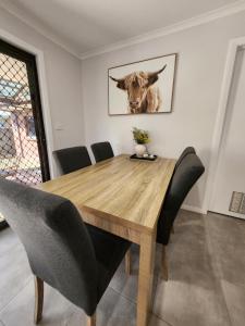 a dining room table with a cow picture on the wall at Lbarza Charming & Convenient 3BR Home close to Hospitals & Sporting Grounds in Shepparton +2 photos