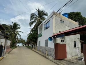an empty street next to a white building with palm trees at Cabaña MariaMar-3 Colombia in Puerto Escondido