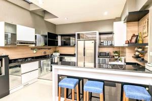 a large kitchen with a bar with blue stools at Cottonwood Villa Kuantan Jogja - Pool Netflix Gym in Ngabean