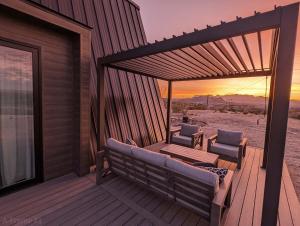 a wooden deck with a couch and two chairs on it at Stardust Big Bend Luxury A-Frame#1 with a fab view in Terlingua