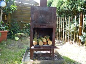 een kachel met een stapel houtblokken in een tuin bij Seeadler - Ferienwohnung in Marienfelde