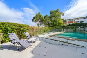 two chairs sitting on a patio next to a swimming pool at Collaroy 3Br Beach Home with Large Pool Ground Floor in Collaroy