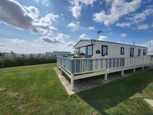 a mobile home on a deck in a yard at Buckley's Retreat - 3 Bedroom Family Caravan overlooking fishing lakes at Golden Palm Resort in Chapel Saint Leonards