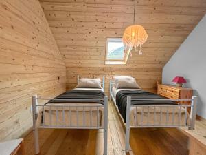 two beds in a room with wooden walls at Maison Style Chalet 4 étoiles avec Jacuzzi- La Sérénité de Sailhan in Camparan