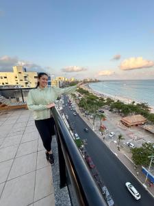 a woman standing on top of a building overlooking a city at O EDIFÍCIO é de frente ao MAR de Pajuçara NEO 2 Qts 2gar - Adm Nutelss in Maceió