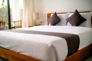 a bedroom with a large white bed with pillows at Rice Fera Guest House in Canggu