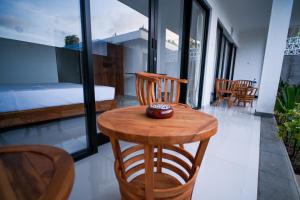 a wooden table and chairs in a room with a bed at Rice Fera Guest House in Canggu