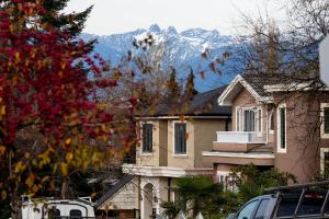 a house with a snow covered mountain in the background at Modern West Coast Contemporary Suite in Vancouver