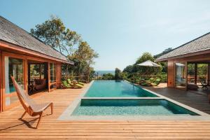 a swimming pool on a wooden deck next to a house at TUNAK Resort Lombok in Bumbang