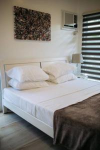 a bedroom with a bed with white sheets and pillows at Casa Bianca Dumaguete in Bolocboloc
