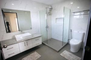 a bathroom with a shower and a sink and a toilet at Casa Bianca Dumaguete in Bolocboloc
