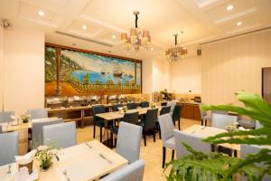 a restaurant with tables and chairs and a painting on the wall at Cap Town Hotel in Ho Chi Minh City