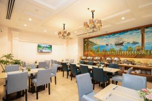 a restaurant with tables and chairs and a large painting at Cap Town Hotel in Ho Chi Minh City