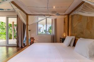 a bedroom with a large white bed and windows at Maharaja Boutique Hotel Zanzibar in Uroa