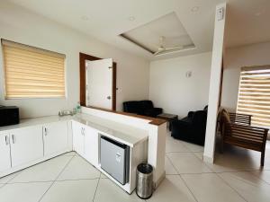 una cucina con mobili bianchi e un soggiorno di WM Resorts a Pooppara