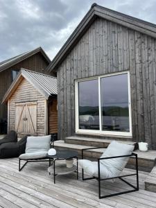 a wooden deck with a table and chairs and a building at Amundøya Boathouse in Vadstensvik