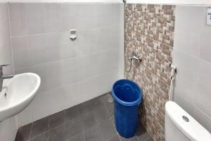 a bathroom with a sink and a blue trash can at Villa Bukit Bunga Syariah RedPartner Pacet in Mojokerto
