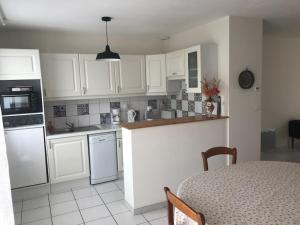 a kitchen with white cabinets and a table in a room at Maison de vacances à Saint Quay Portrieux in Saint-Quay-Portrieux
