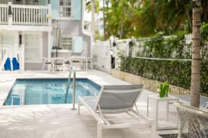 a swimming pool with a chair and a table and a swimming pool at Fitch Lodge - Key West Historic Inns in Key West