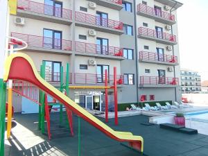 a playground in front of a building with a slide at Kharisma Hotel in Mamaia Nord