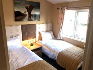 a bedroom with two beds and an elephant painting on the wall at Hot Tub Safari Lodge in Kinmel Bay +5 photos