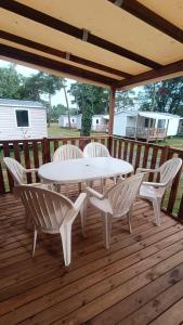 a white table and chairs on a wooden deck at Mobil Home climatisé 3 chambres 6 Pers Tout Confort 510PM in La Boissière-de-Montaigu