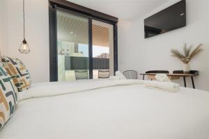 a bedroom with a large white bed with a large window at Brand-new beachside apartment, with spacious terrace and exceptional amenities, in Fuengirola in Fuengirola