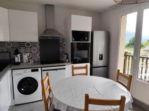 eine Küche mit einem Tisch und einem Kühlschrank in der Unterkunft Ossau T2 5 personnes piscine climatisation 1 chambre draps serviettes inclus parking moustiquaires lave vaisselle lave linge tout confort in Bielle