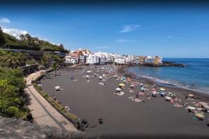 a beach with a bunch of people laying on the sand at La Sirena Playa A in Puerto de la Cruz