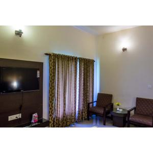 a room with two chairs and a flat screen tv at Goldfield Club & Lake Resort, Kumarakom in Kumarakom