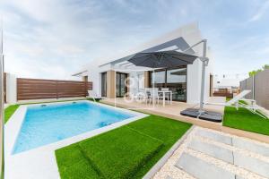 a villa with a swimming pool and an umbrella at Villa Bienvida luxury and well-being by OYOOSTAYS in Orihuela