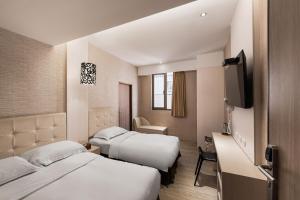 una camera d'albergo con due letti e una televisione di The Riverside Hotel Hengchun a Città Vecchia di Hengchun