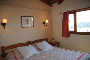 a bedroom with a bed with two pillows and a window at Alun Bungalows Apart in San Carlos de Bariloche