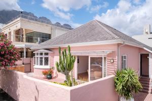 a pink house with mountains in the background at Casa Caprice - a 3 bed home steps from the beach in Cape Town