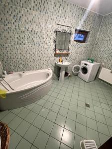 a bathroom with a tub and a washing machine at Vila Rosu in Pucioasa