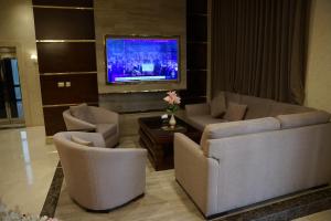 a living room with two couches and a tv at Big Ben Hotel Suites in Amman
