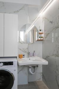 a white bathroom with a sink and a washing machine at HomEasy Apartments - Kalamata Central Getaways with Private Parking in Kalamata +61 photos