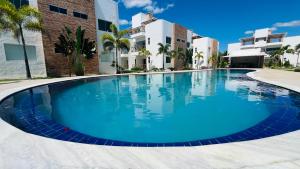 a large blue swimming pool in front of a building at Condomínio Vila do Mar - Apartamento 3 quartos in Luis Correia