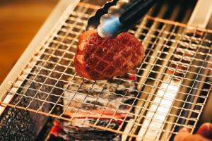 a piece of meat being cooked on a grill at 森のオーベルジュ 三 みつ - 旧 森厚真hotel CHUPKI - in Chitose