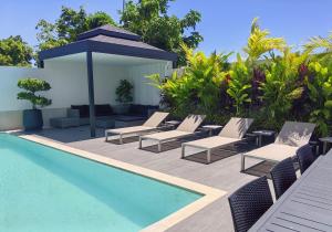 ein Swimmingpool mit Liegestühlen und einem Sonnenschirm neben einem Pool in der Unterkunft Bangtao Luxury Pool Villa - Prymana in Phuket