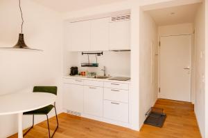 a kitchen with white cabinets and a table at Boutique Studio, Bundeshausblick I Nähe Altstadt in Bern